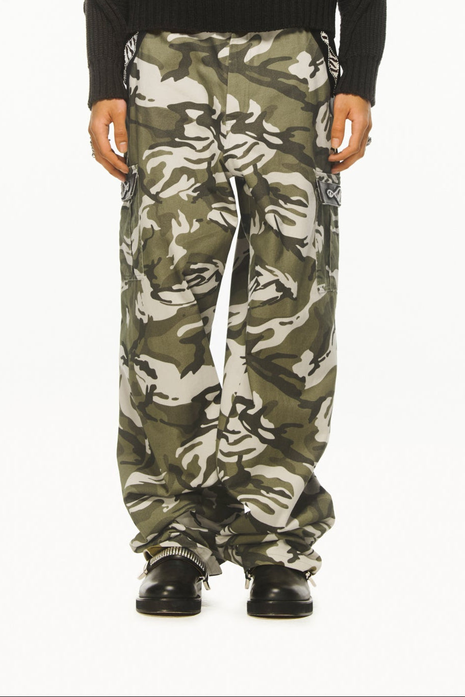 A male model wearing BLUEMARBLE camouflage cargo pants in soft-touch cotton twill featuring a relaxed fit, pony and leather detailing at the pockets, two side pockets, two cargo pockets, two back patch pockets and adjustable waist tabs styled with dark grey knitted jumper. 