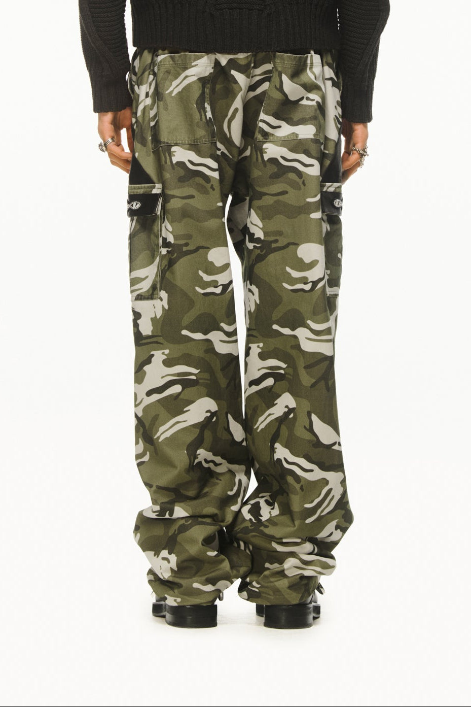 A male model wearing BLUEMARBLE camouflage cargo pants in soft-touch cotton twill featuring a relaxed fit, pony and leather detailing at the pockets, two side pockets, two cargo pockets, two back patch pockets and adjustable waist tabs styled with dark grey knitted jumper. 