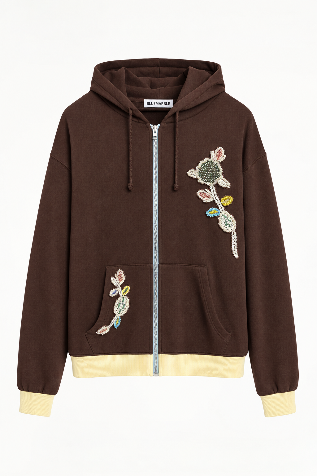 BLUEMARBLE brown 100% cotton zip-up hoodie featuring a slightly oversized fit, color-block design, hand-embroidered multicolored botanical beading on brown leather patches, light blue zip, washed yellow ribbed cuffs and hem, and drawstring hood.
