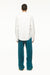Male model wearing a BLUEMARBLE white poplin shirt featuring molten metal studs along the shoulders and armholes, raw-edge detailing and a slightly oversized fit, styled with duck green workwear pants against a white studio background.